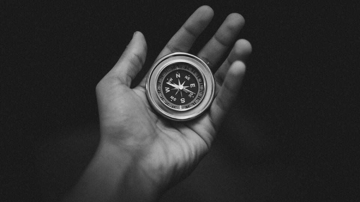 A black and white photo of a hand with a compass in the palm 